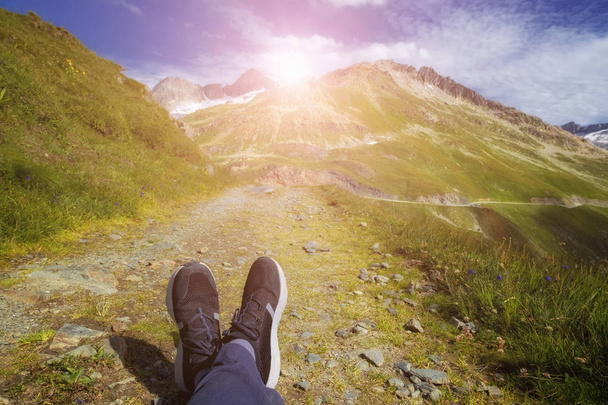 Jalat matkustaja tyylikäs lenkkarit istuu korkealla vuorella
 - Valokuva, kuva