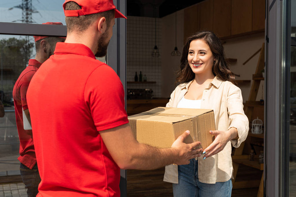 delivery man giving cardboard box to happy woman  - Fotó, kép