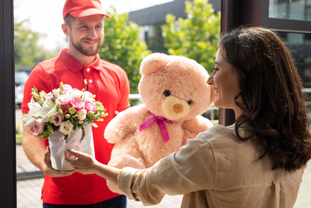 selective focus of happy woman receiving gifts from delivery man   - Photo, image