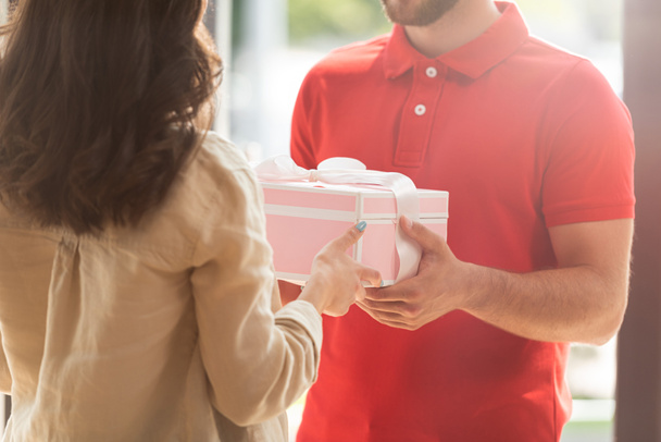 cropped view of delivery man giving pink present to young woman  - Photo, Image