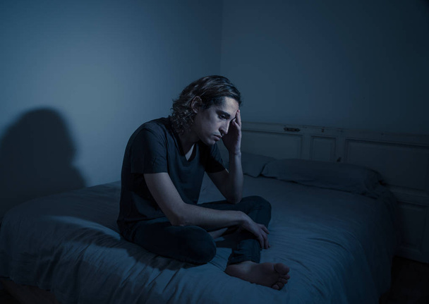 Devastated millennial man crying sad feeling hurt and hopeless suffering Depression. Depressed teenager victim of bullying or abuse sitting on bed alone in despair at night. In teenage Mental health. - Фото, изображение