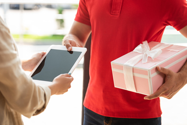 cropped view of delivery man holding pink present and giving digital tablet to woman  - Фото, зображення