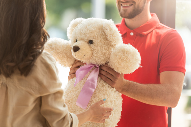 bijgesneden weergave van gelukkige bebaarde man geven teddybeer aan vrouw  - Foto, afbeelding