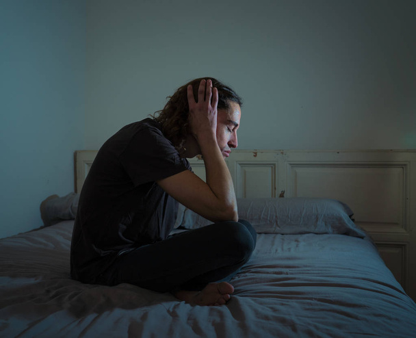 Devastated millennial man crying sad feeling hurt and hopeless suffering Depression. Depressed teenager victim of bullying or abuse sitting on bed alone in despair at night. In teenage Mental health. - Фото, изображение