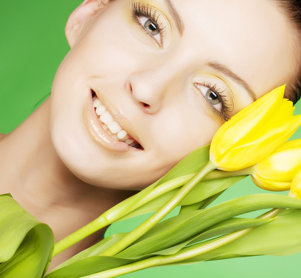 Woman with yellow flowers on green background - Foto, afbeelding