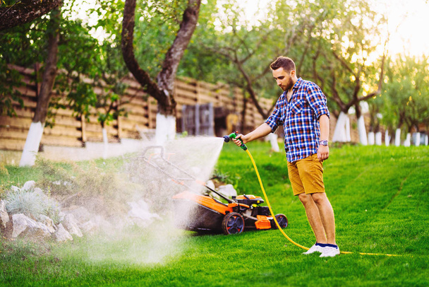 Portrait of caucasian man watering lawn in backyard using hose and water - Foto, Imagem