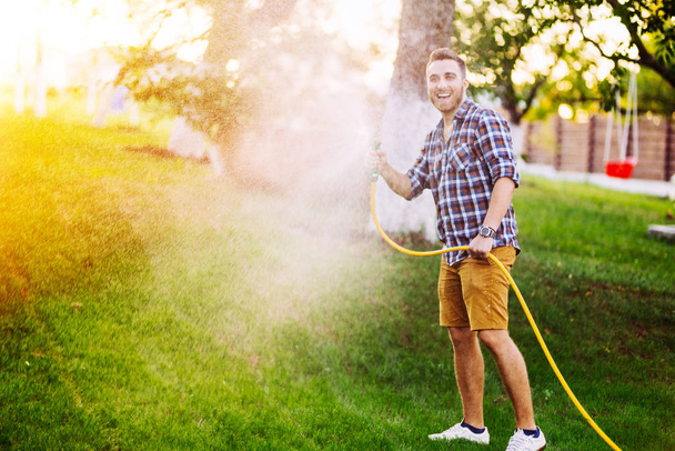 Gardening details - man playing with hose and watering the lawn - 写真・画像