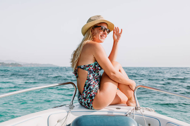 Teknenin pruvası üzerinde oturan genç kadın denizde manzaranın tadını çıkarıyor - Fotoğraf, Görsel