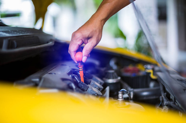 Controleer het oliepeil in de gele auto motor. Monteur auto controle  - Foto, afbeelding