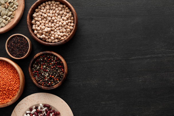 ylhäältä näkymä musta kvinoa, punainen linssi, pavut, kurpitsan siemenet, pippurit ja kikherne tummalla puupinnalla
 - Valokuva, kuva