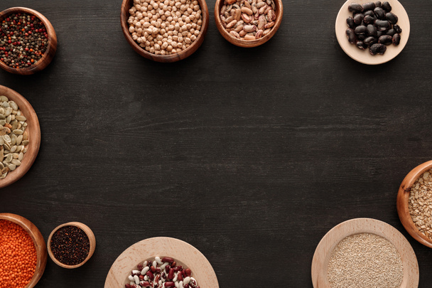 vista superior de legumbres y cereales en cuencos sobre superficie de madera oscura con espacio para copiar
 - Foto, Imagen