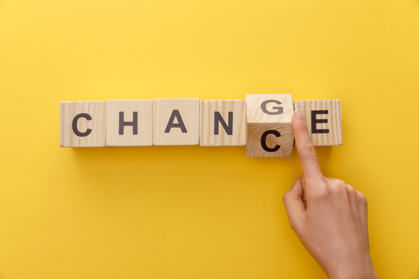 περικομμένη όψη της γυναίκας εναλλαγή ξύλινο κύβο από το Word αλλαγή σε ευκαιρία σε κίτρινο φόντο - Φωτογραφία, εικόνα