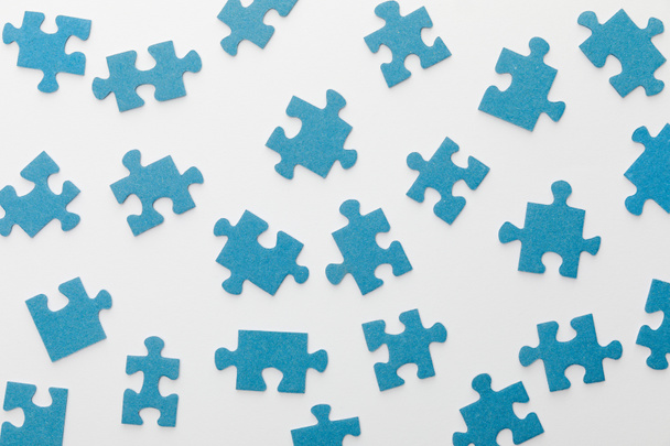 top view of scattered blue jigsaw puzzle on white background - Foto, Imagem