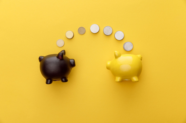 top view of piggy banks with coins on yellow background - Photo, Image