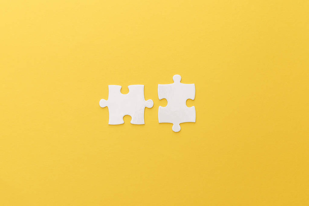Draufsicht auf weiße Puzzleteile auf gelbem Hintergrund - Foto, Bild