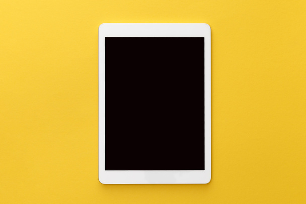 bovenaanzicht van digitale tablet met leeg scherm op gele achtergrond - Foto, afbeelding