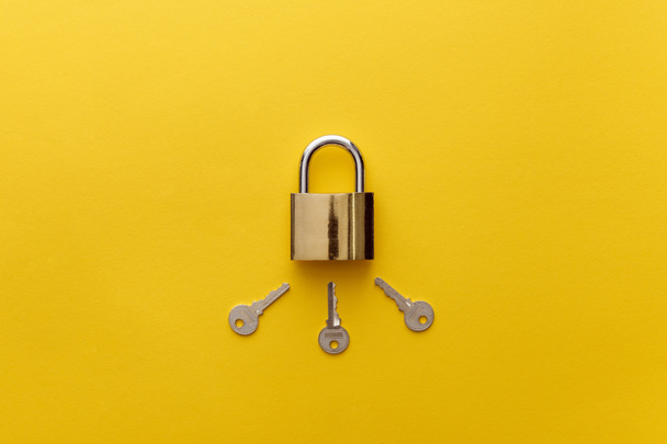 top view of metal padlock with keys on yellow background - Photo, Image
