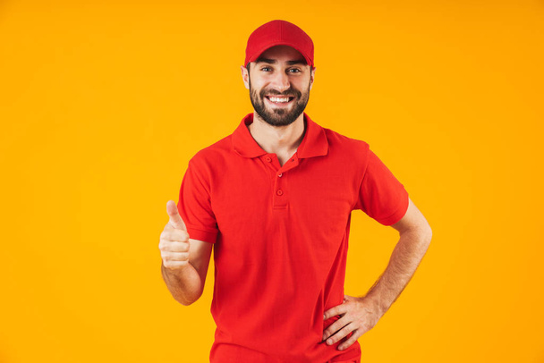 Portrait of attractive delivery man in red t-shirt and cap smili - Photo, Image