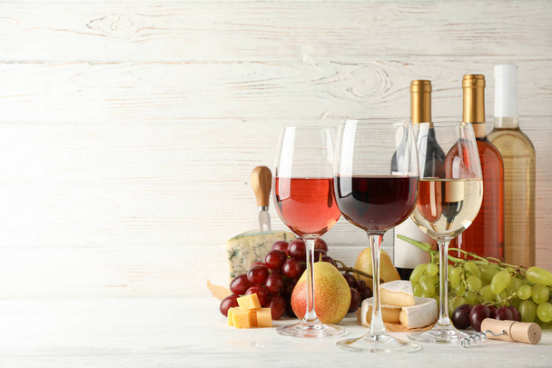 Fruits, cheese, bottles and glasses with different wine on white - Fotografie, Obrázek