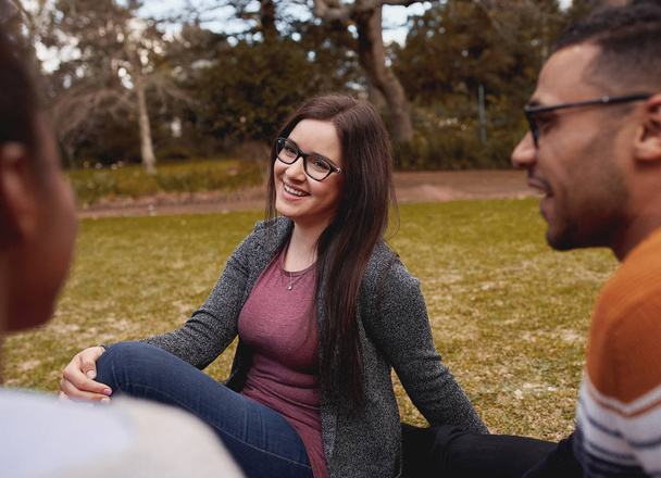 Portrait of a beautiful smiling young woman wearing eyeglasses relaxing with her friend in the park - Foto, Bild