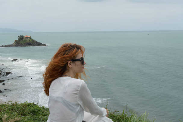  Red haird girl in long white skirt traveler in nature looking to beautiful view and small island in Vung Tau.Relax time on holiday concept travel . - Фото, зображення