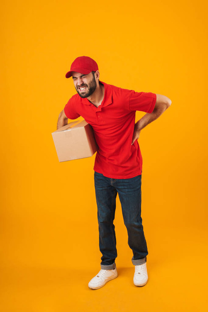 Full length portrait of upset delivery man in red uniform touchi - Фото, изображение