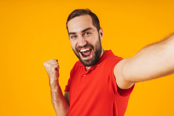 Portrait of joyful man in red t-shirt laughing and rejoicing whi - Foto, Bild