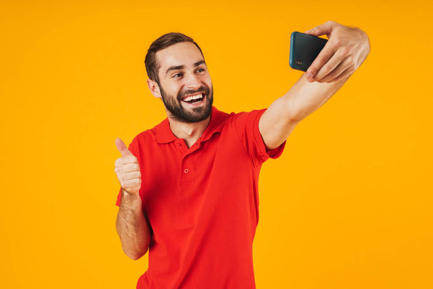 Portrait of attractive man in red t-shirt laughing and showing t - Fotografie, Obrázek