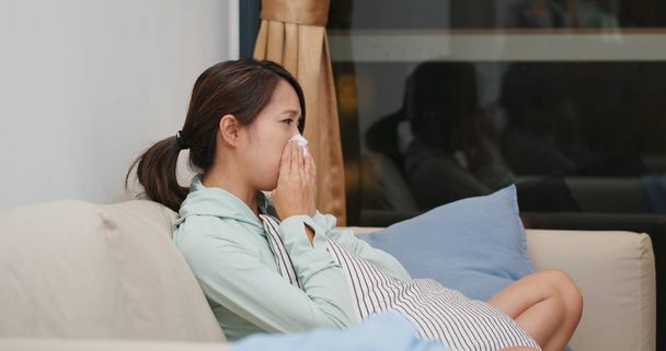 Donna malata starnutire e sedersi sul divano a casa
 - Foto, immagini