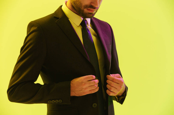 Cropped image of confident handsome businessman in formal suit touching his jacket - 写真・画像