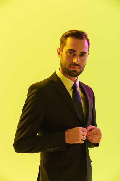Image of young serious businessman in formal suit touching his jacket - Photo, image