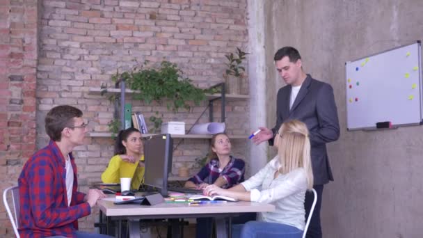 μάνατζερ σε στολή εκπαιδεύει νέους εργαζομένους στο γραφείο, επικοινωνία σε ομάδα επιχειρήσεων σε ένα τραπέζι - Πλάνα, βίντεο