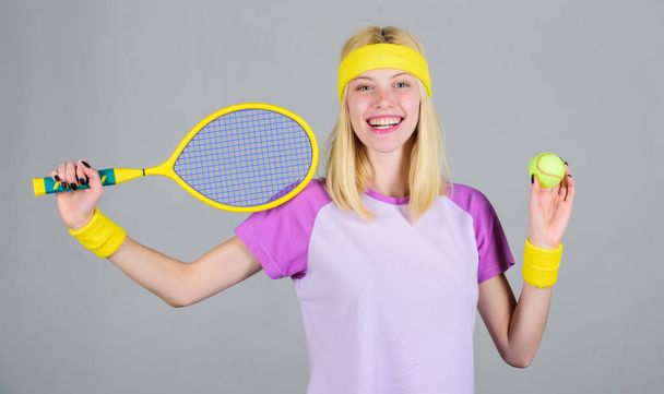 Tennis sport and entertainment. Tennis club concept. Girl adorable blonde play tennis. Sport for maintaining health. Athlete hold tennis racket in hand on grey background. Active leisure and hobby - Zdjęcie, obraz