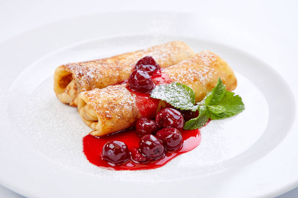 sweet pancakes with cherries on white plate, close-up  - Φωτογραφία, εικόνα