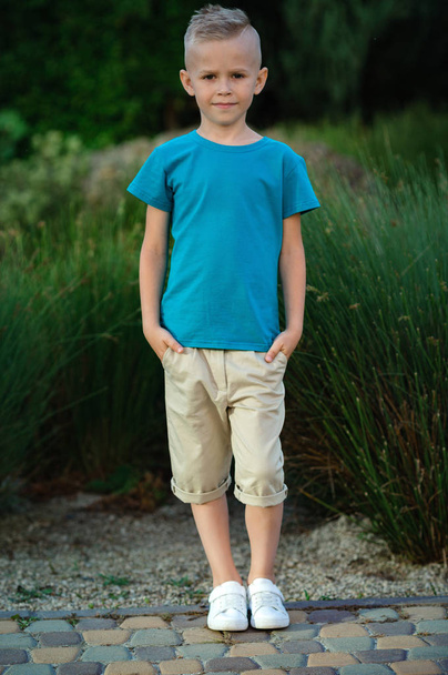 Porträt eines kleinen blonden Jungen, der draußen posiert - Foto, Bild