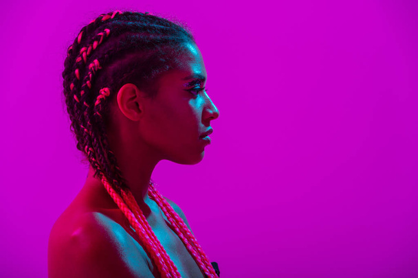 Young african naked woman posing isolated over purple neon lights wall background - Φωτογραφία, εικόνα