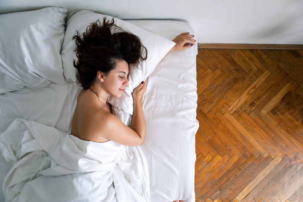 joven bonita mujer caucásica durmiendo en la cama con sábanas blancas
 - Foto, imagen