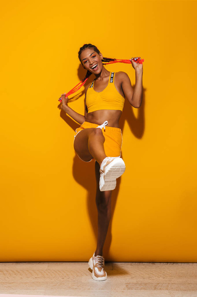 Image of beautiful african american woman dressed in tracksuit dancing and smiling at camera - Zdjęcie, obraz