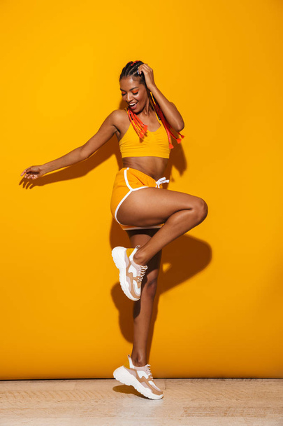 Image of beautiful african american woman dressed in tracksuit dancing and laughing - Foto, Bild