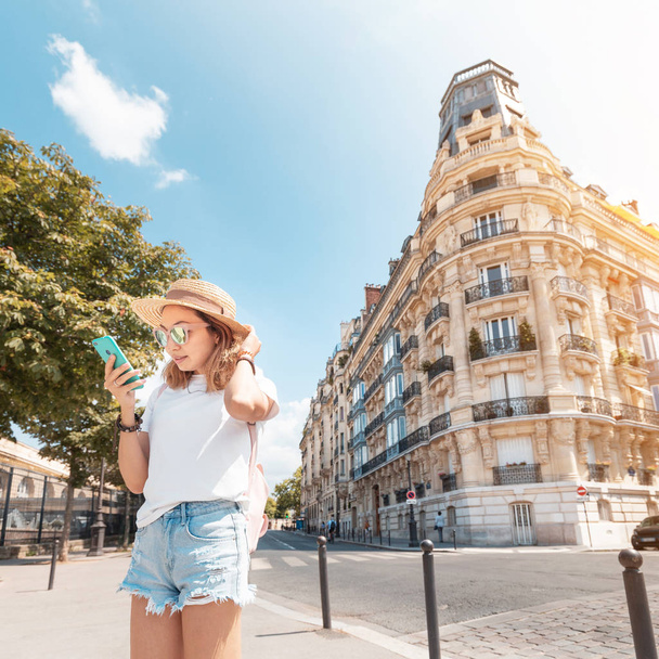 A woman stands near a typical Parisian residential corner house. Concept of apartments or hotels for tourists - Photo, Image