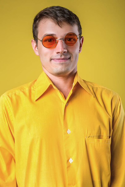 Портрет молодого чоловіка в сонцезахисних окулярах, що позує на жовтому тлі
. - Фото, зображення