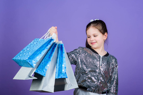 Black friday. Sale discount. Shopping day. Child hold bunch packages. Kids fashion. Birthday girl. Surprise gift. Girl with shopping bags violet background. Shopping and purchase. Get better looking - Фото, изображение