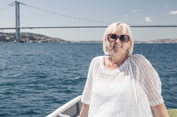 Femme attrayante souriante dans des lunettes de soleil sur le grand navire blanc ou yacht. Croisière, voyage et aventure pour retraité actif. Belle mer bleue sur le fond
. - Photo, image