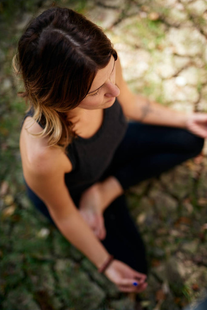 Top view of peaceful Caucasian woman in nature sitting on ground in lotus yoga pose and meditating. Summer time. - Photo, image