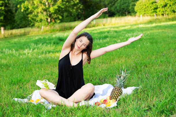 jovem mulher sentada ao ar livre na natureza e está se alongando
 - Foto, Imagem