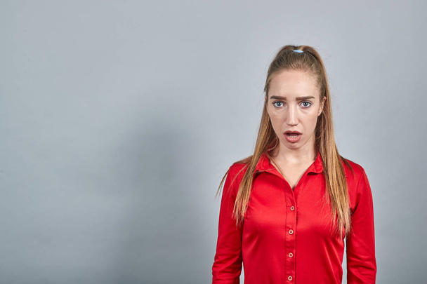meisje brunette in rode blouses over geïsoleerde witte achtergrond toont emoties - Foto, afbeelding