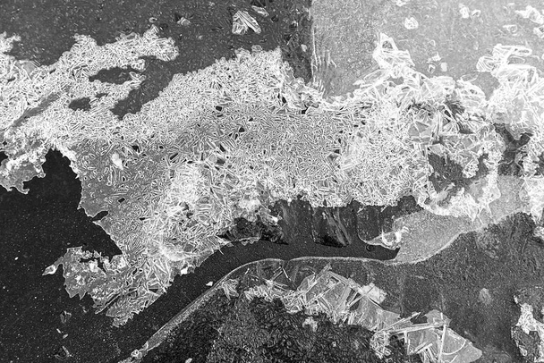 舗装上の氷の地殻の質感、黒と白の写真、背景 - 写真・画像