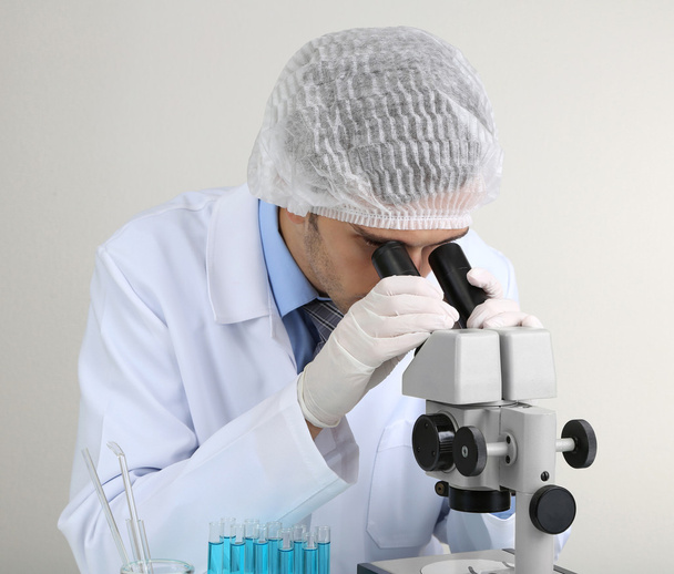 Young laboratory scientist looking at microscope in lab - Foto, Imagen