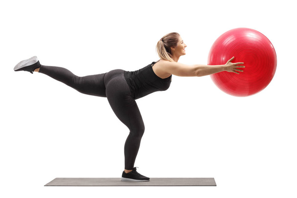 Frau trainiert mit Fitnessball und hebt ein Bein - Foto, Bild