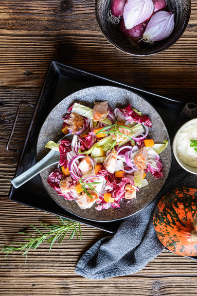 Salada de legumes com chicória vermelha e branca, pedaços de truta assada, cebola e abóbora Hokkaido assada
 - Foto, Imagem